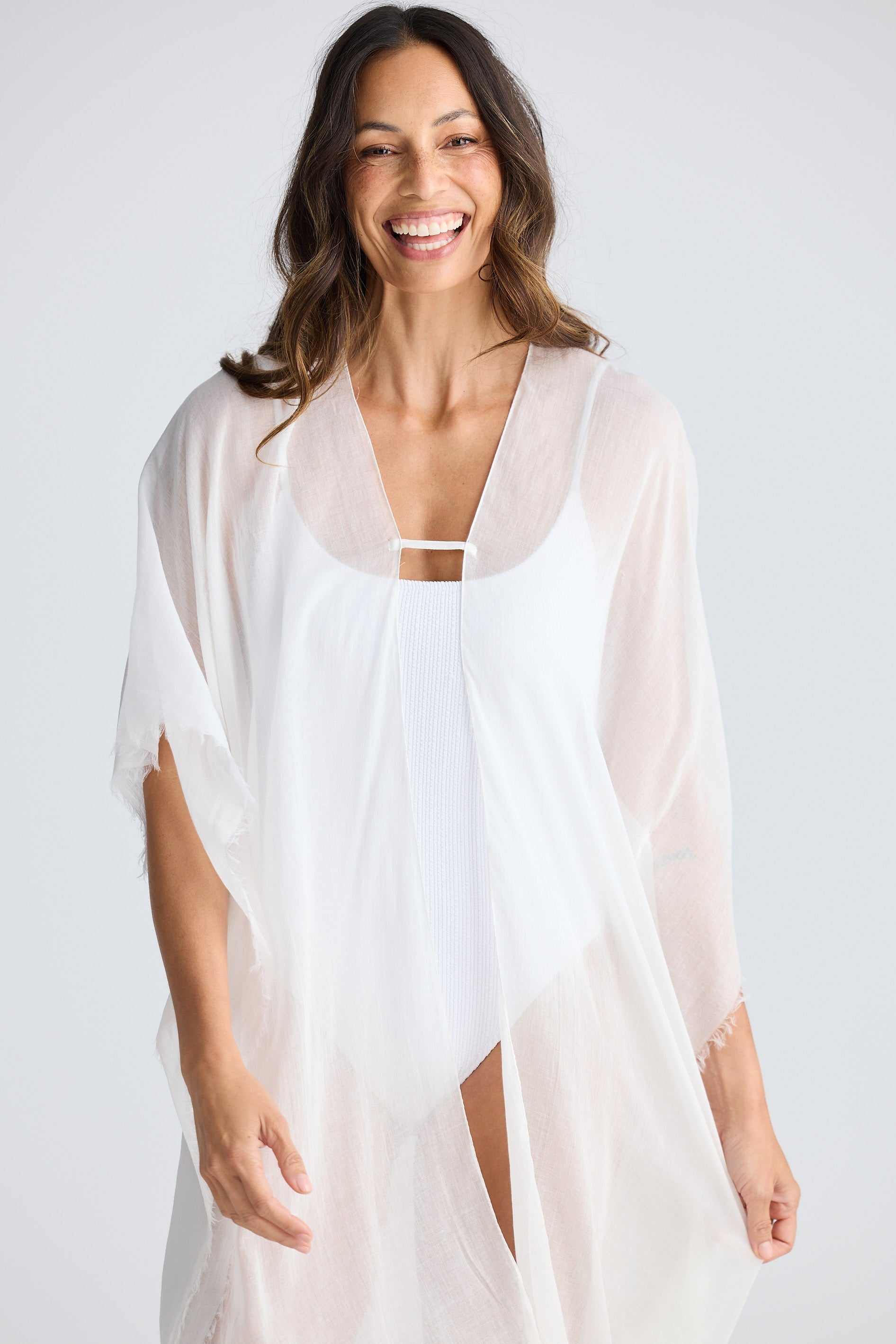 Woman wearing a white cover-up against a plain background