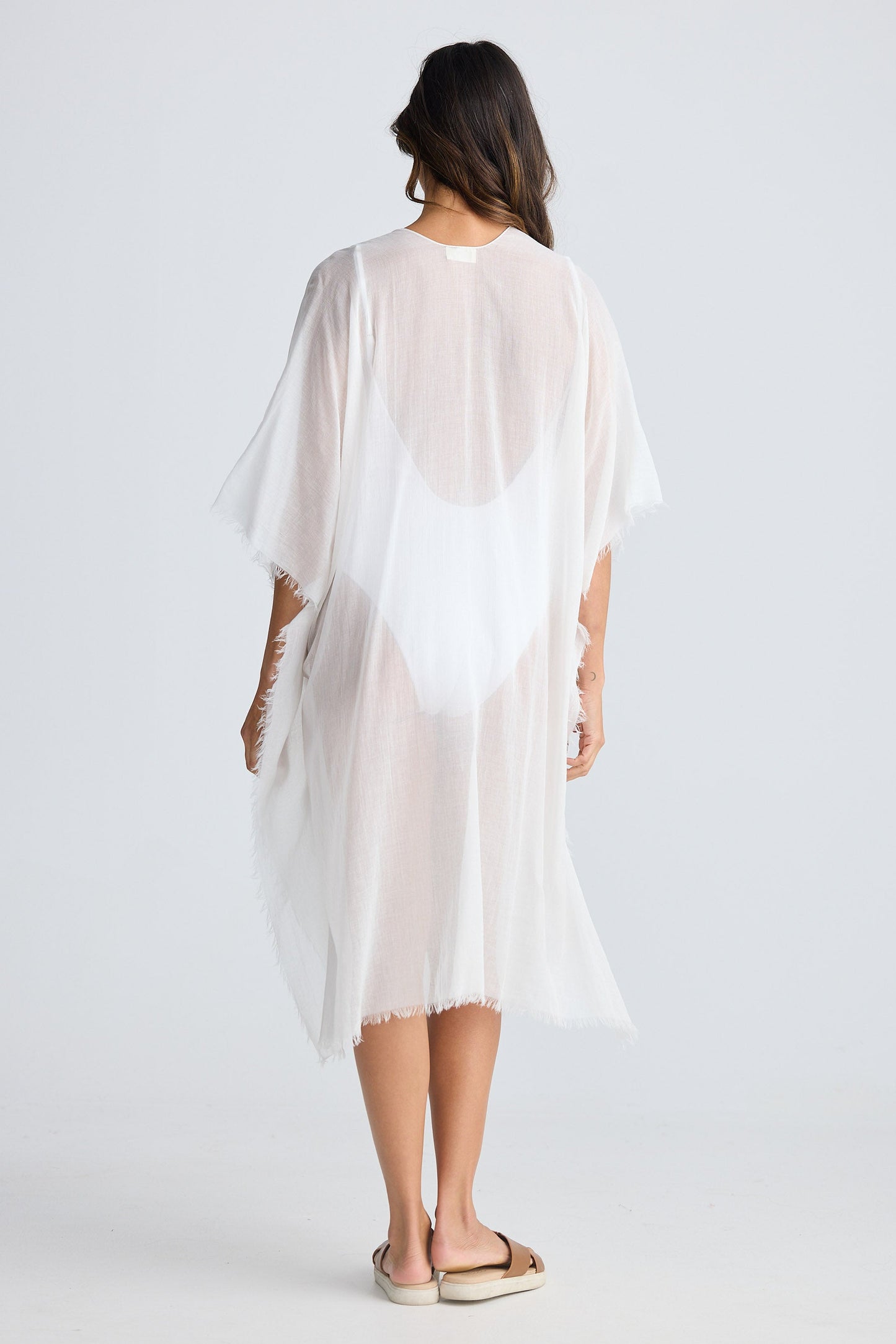 Woman wearing a white sheer cover-up against a white background