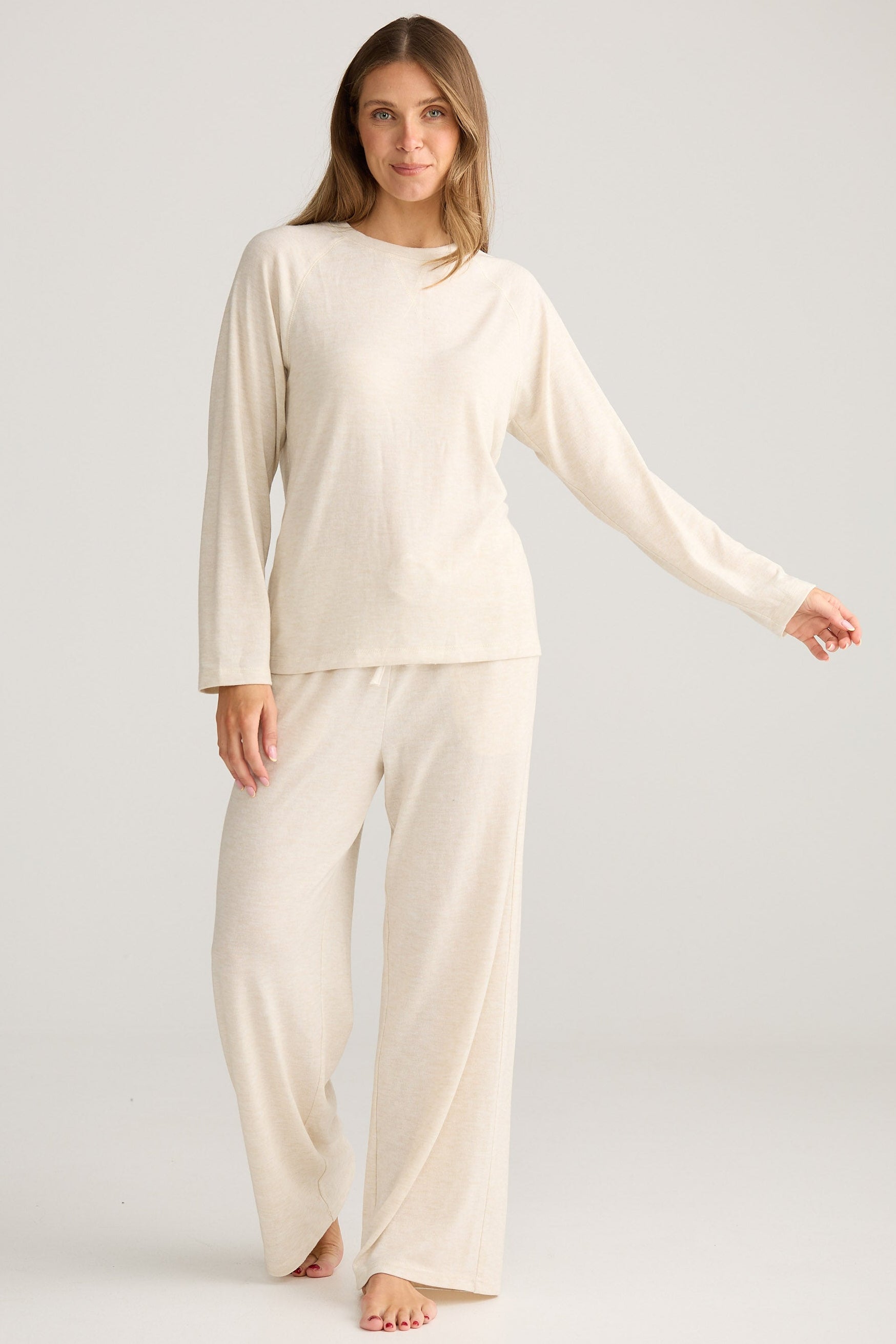 Woman wearing a cream-colored pajama set on a plain background