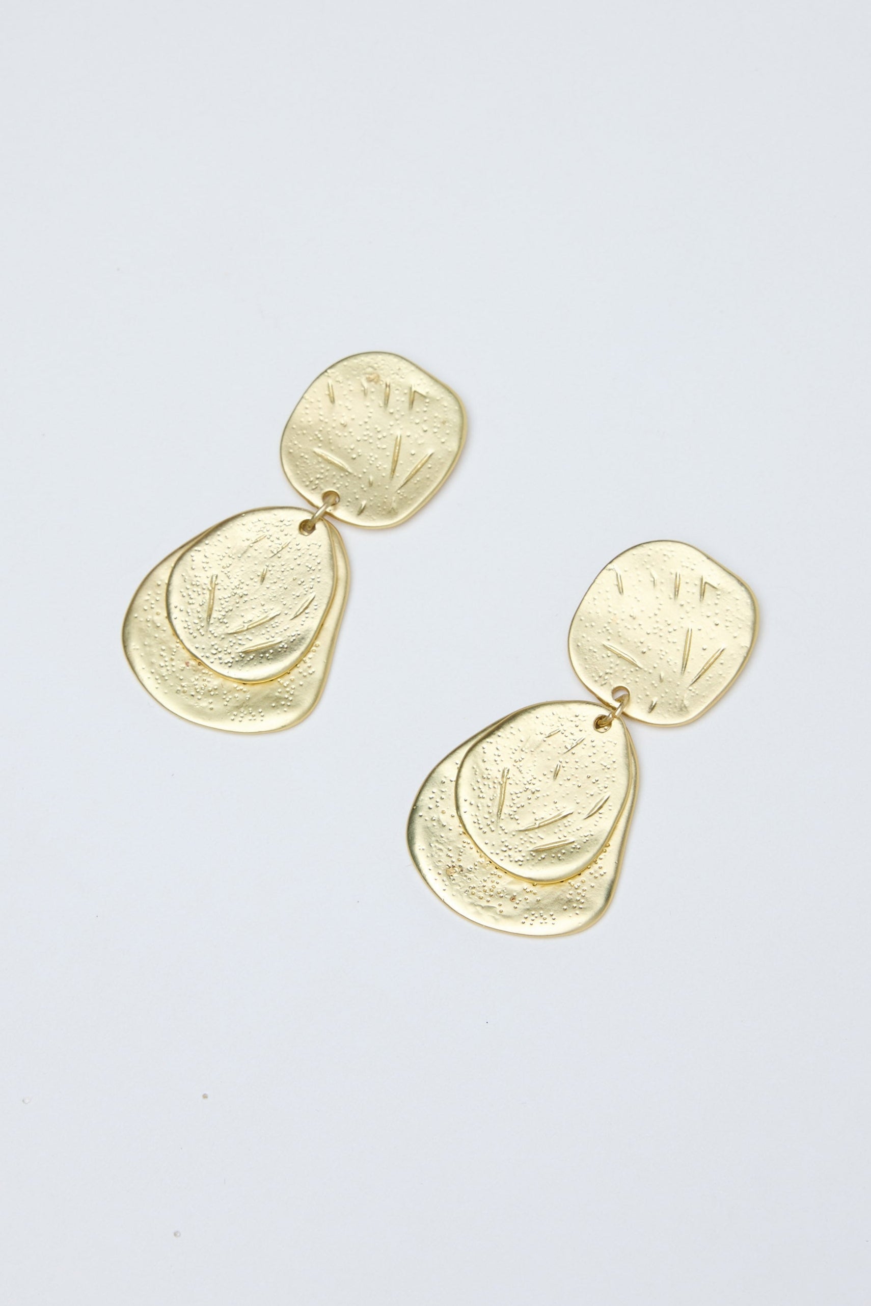 Gold earrings on a light gray background