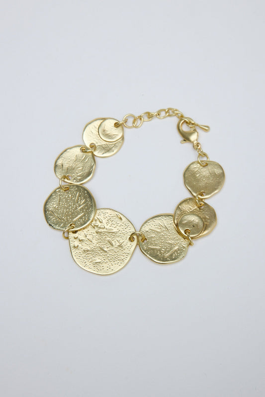 Gold bracelet with circular links on a light gray background