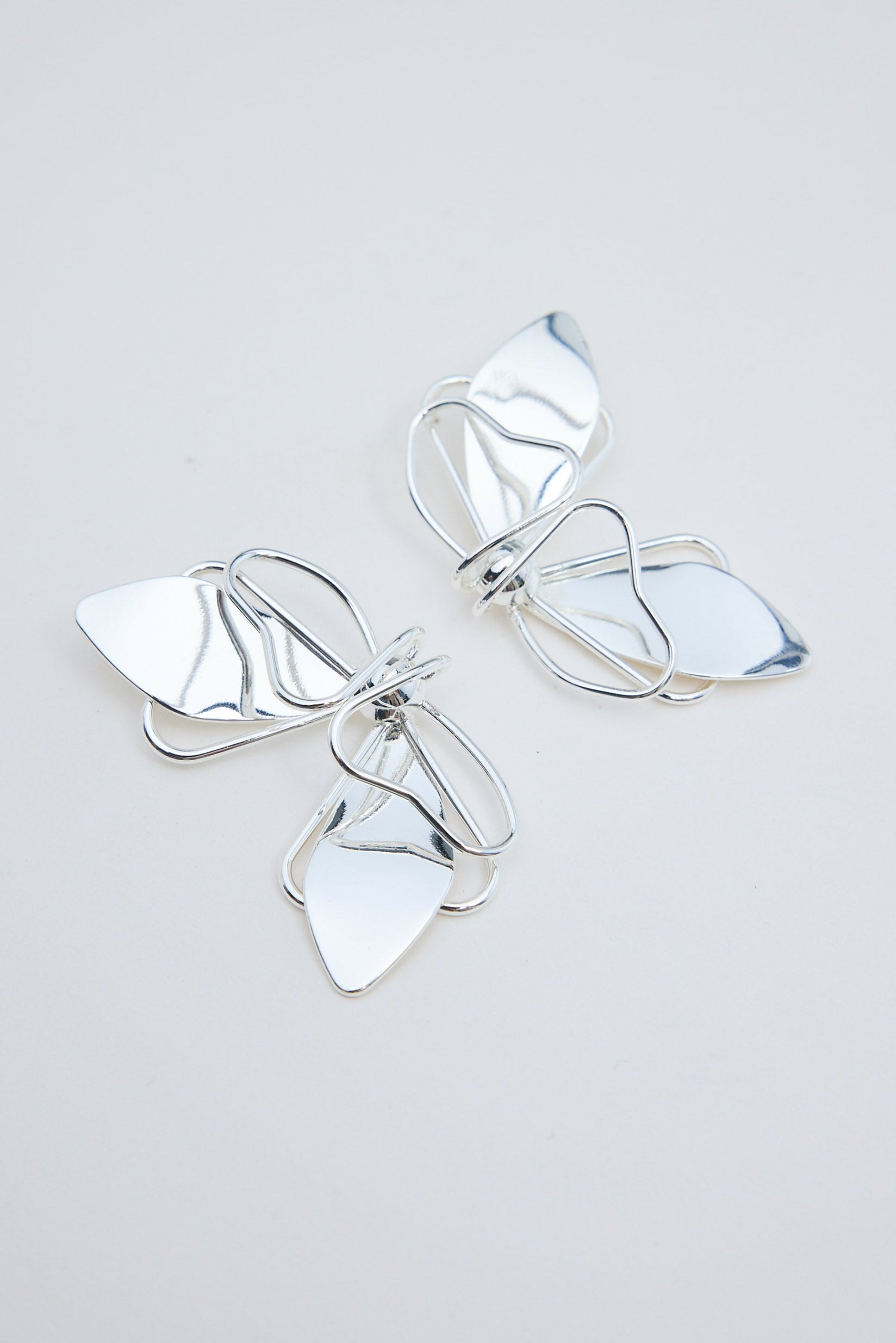 Pair of silver butterfly-shaped earrings on a light gray background