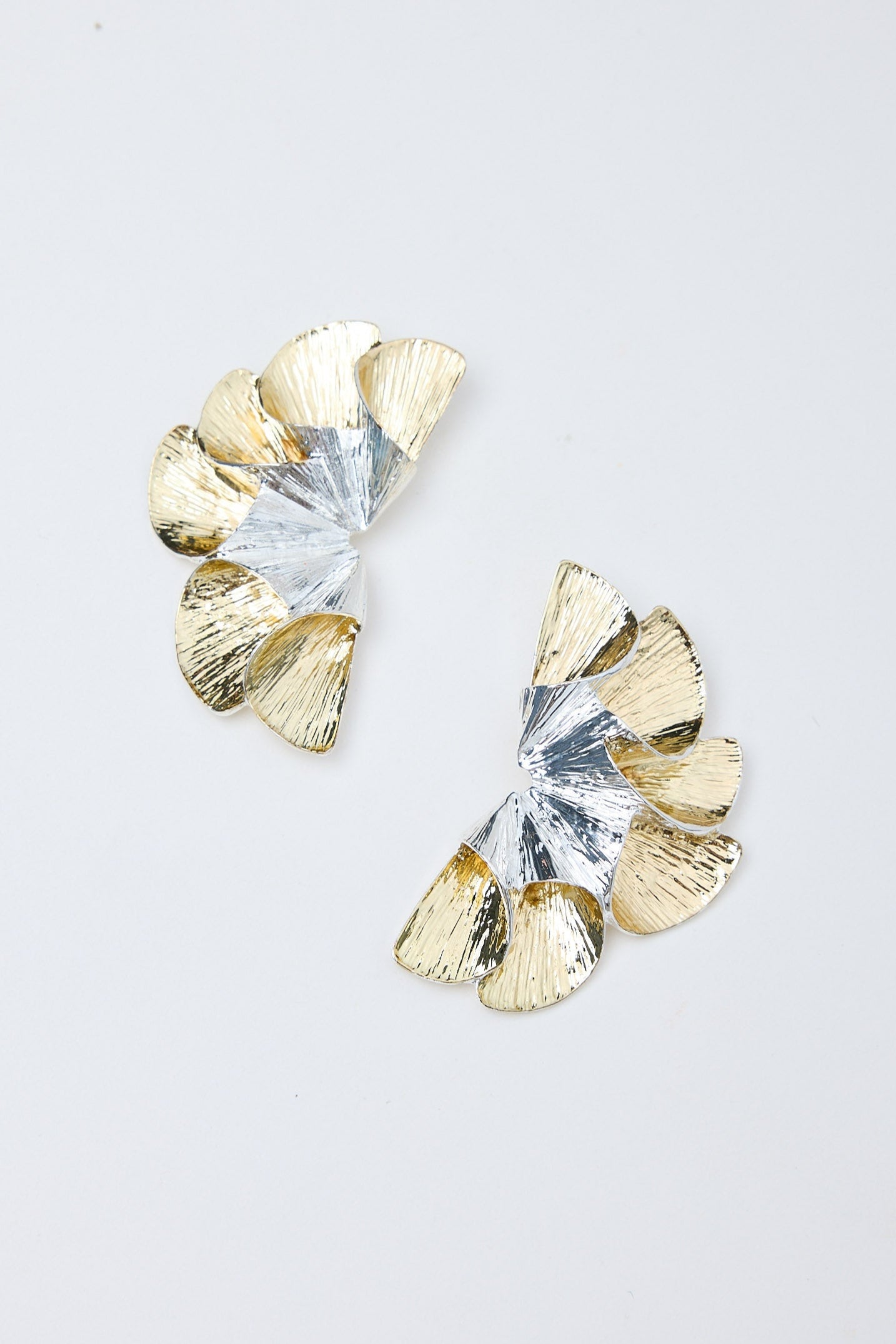Pair of gold and silver earrings on a light gray background