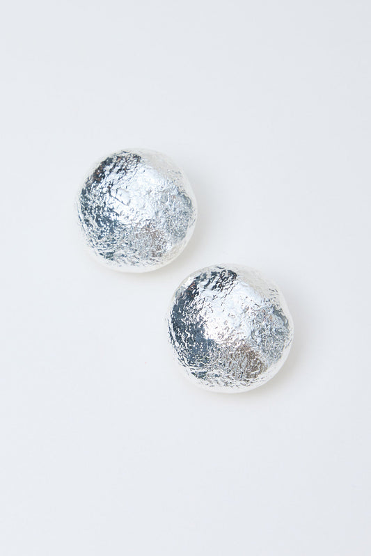 Pair of silver textured round earrings on a light gray background