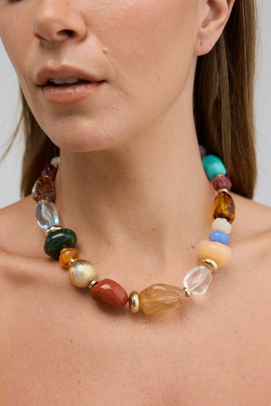 Multicolored beaded necklace worn by a person against a neutral background