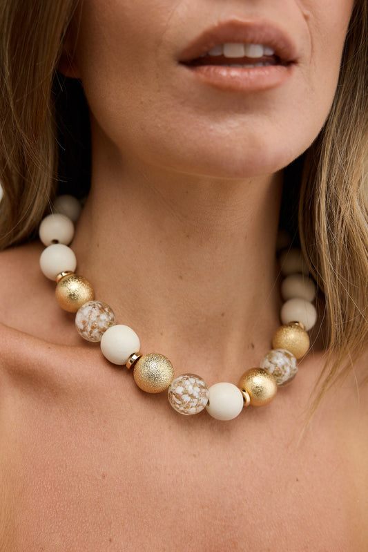 Close-up of a woman wearing a beaded necklace with a blurred background