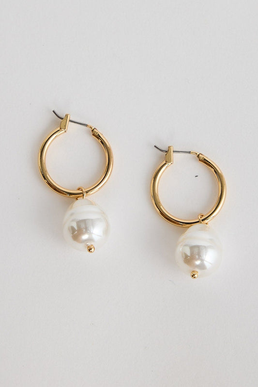 Gold hoop earrings with pearl drops on a light gray background