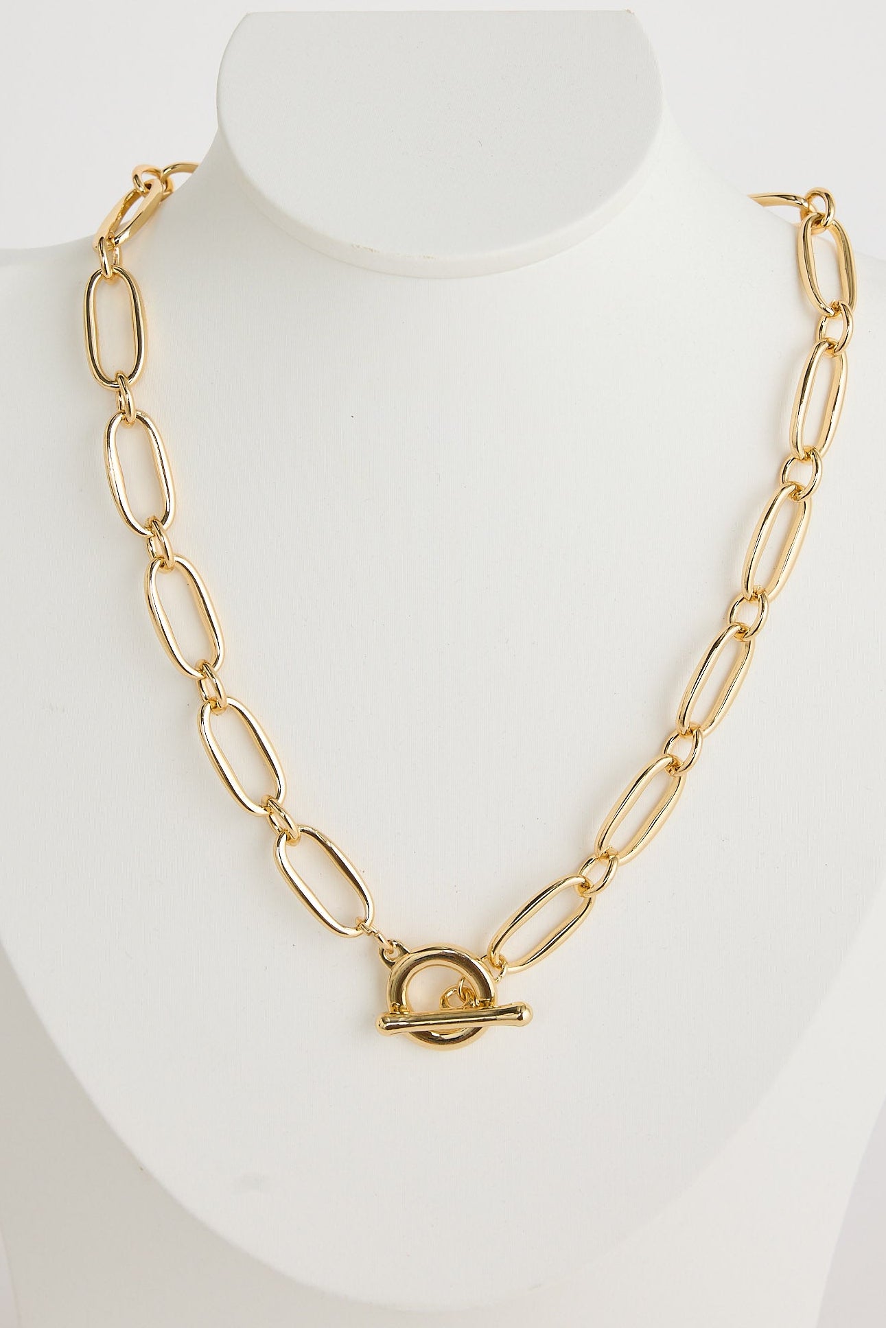 Gold chain necklace on a mannequin bust against a white background