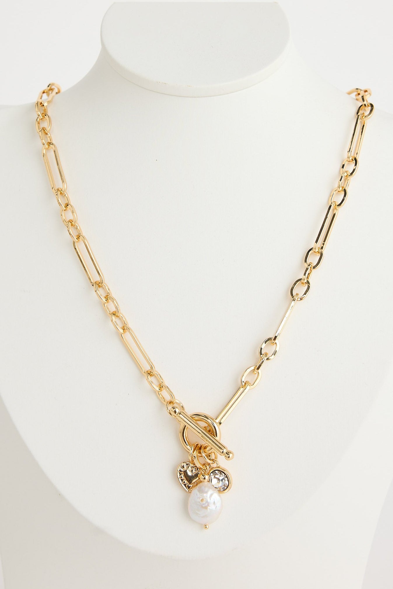 Gold necklace with a pearl pendant on a mannequin bust against a white background