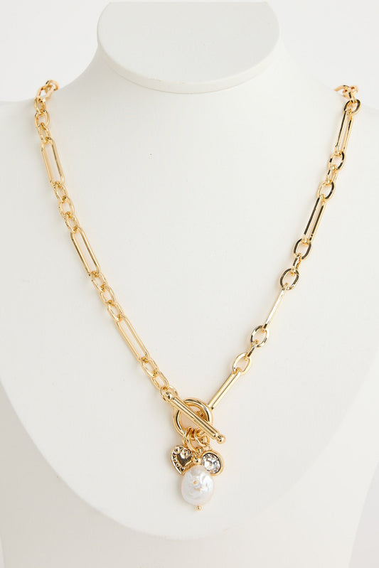 Gold necklace with a pearl pendant on a mannequin bust against a white background