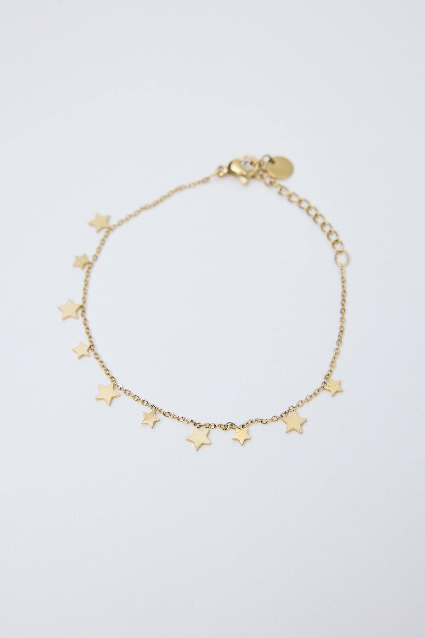 Gold bracelet with star charms on a light gray background