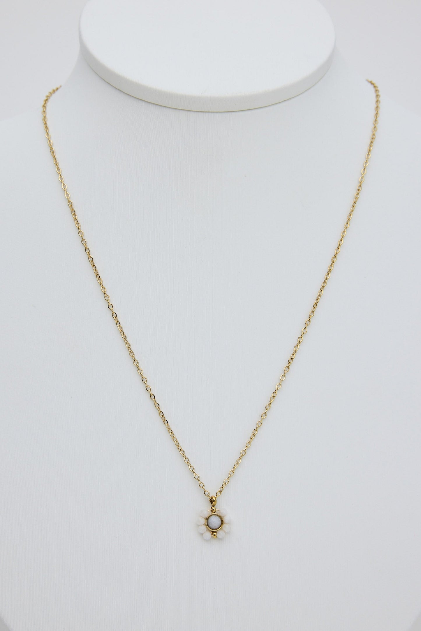 Gold necklace with a small pendant on a white mannequin bust