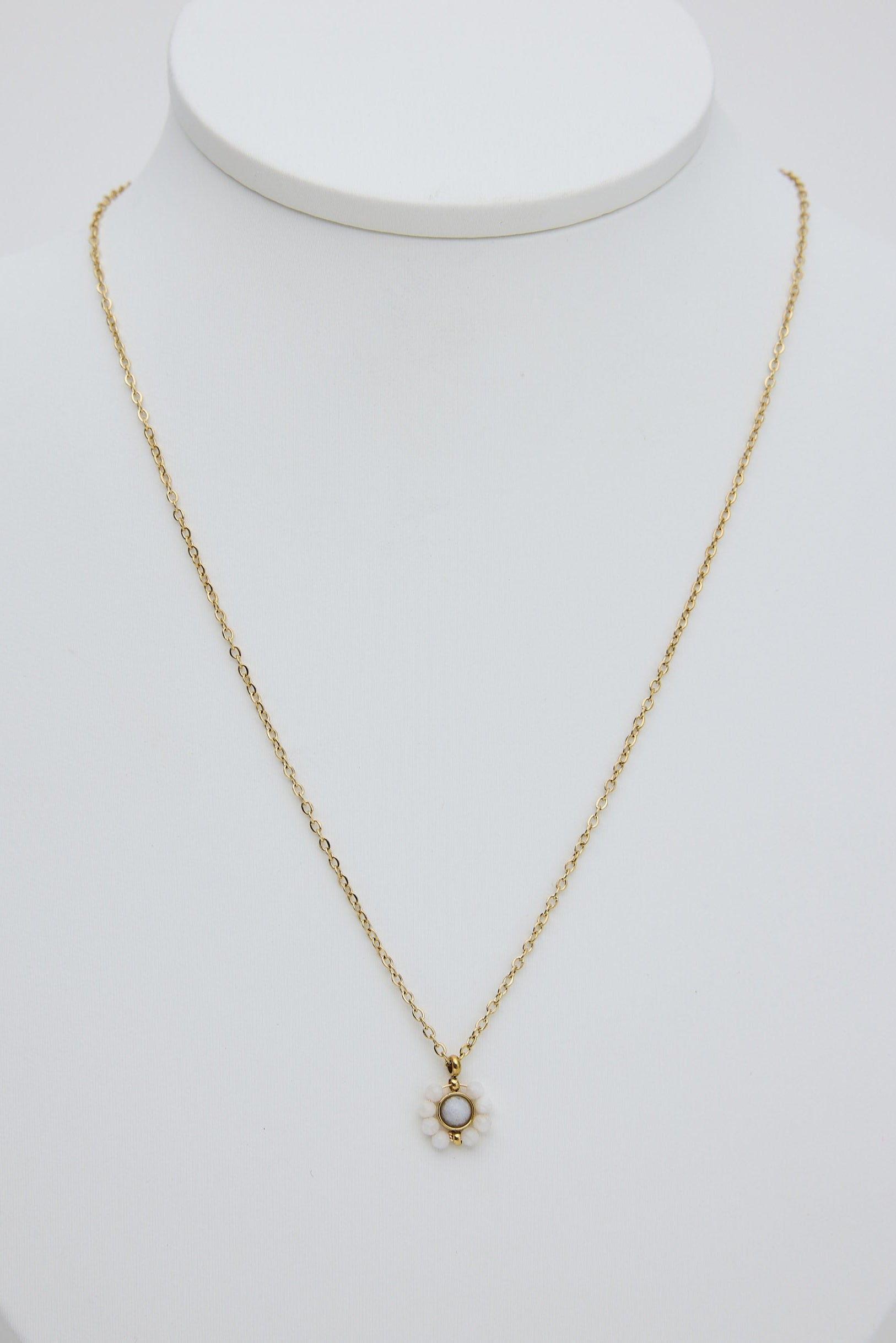Gold necklace with a small pendant on a white mannequin bust