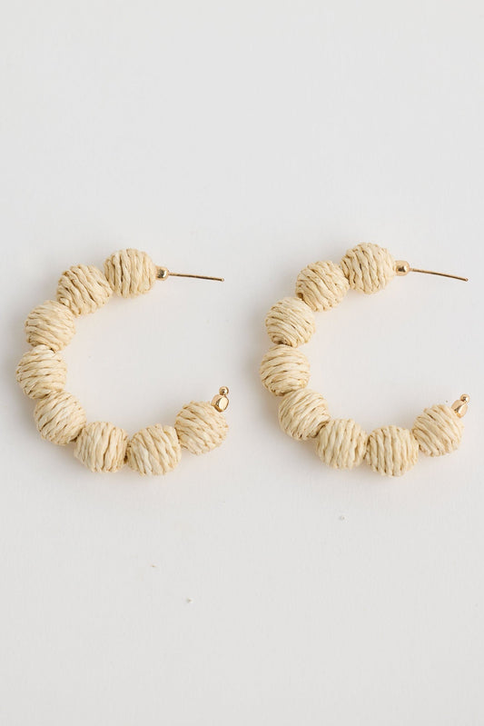 Close-up of natural waldorf hoops earrings on white background.