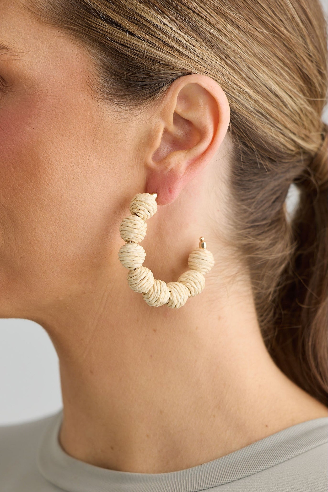 Close-up of natural waldorf hoops earrings on white background.