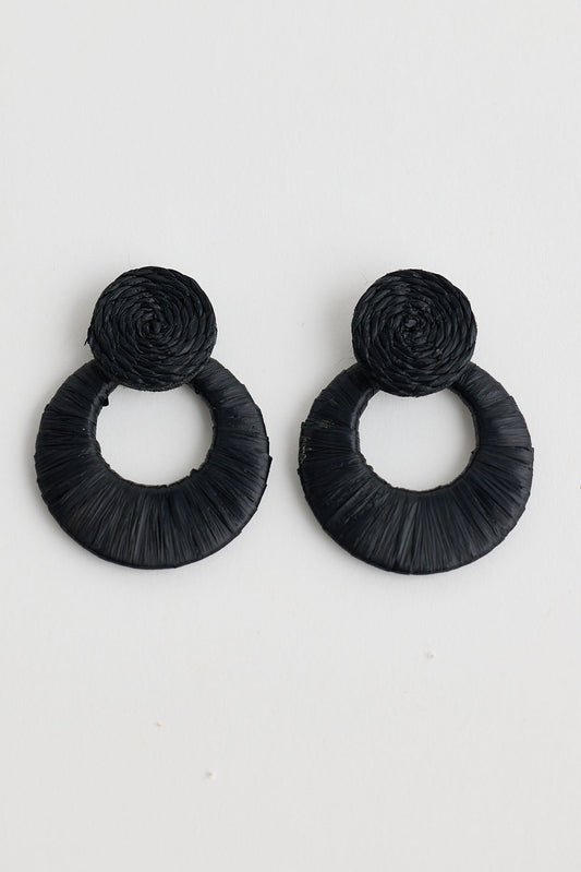 Pair of black raffia earrings on a light gray background