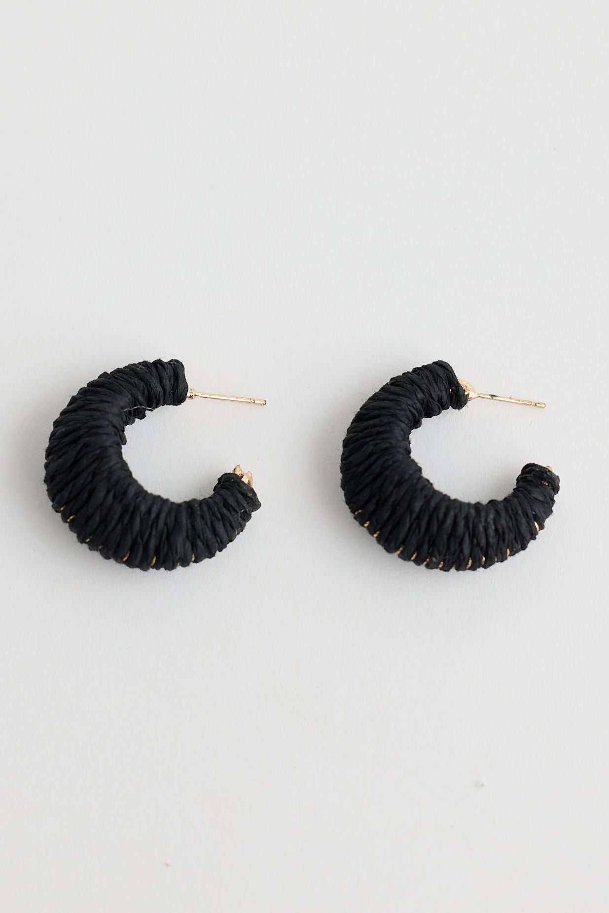 Black raffia hoop earrings on a light gray background