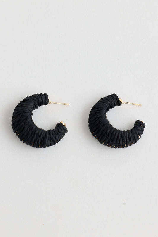 Black raffia hoop earrings on a light gray background