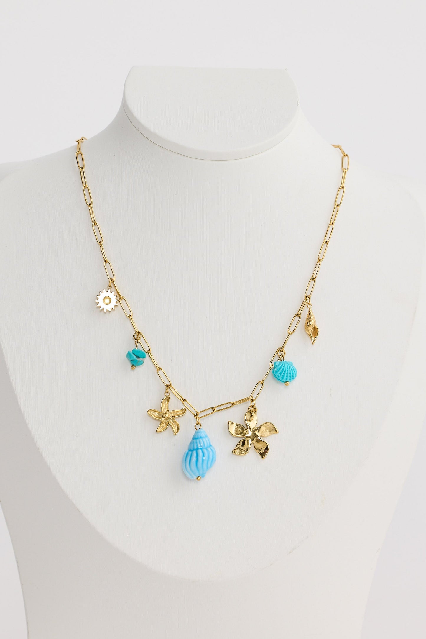 Gold necklace with blue pendants on a mannequin against a white background