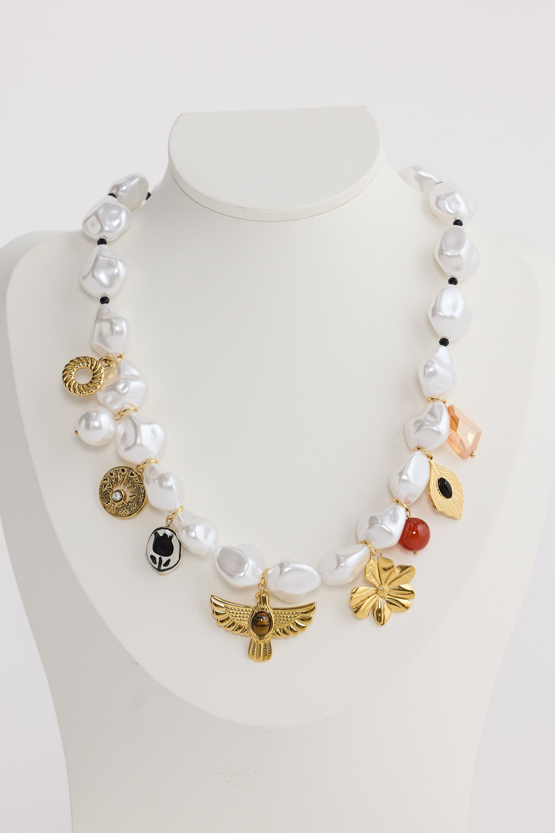 Necklace with various beads and charms on a mannequin bust against a white background