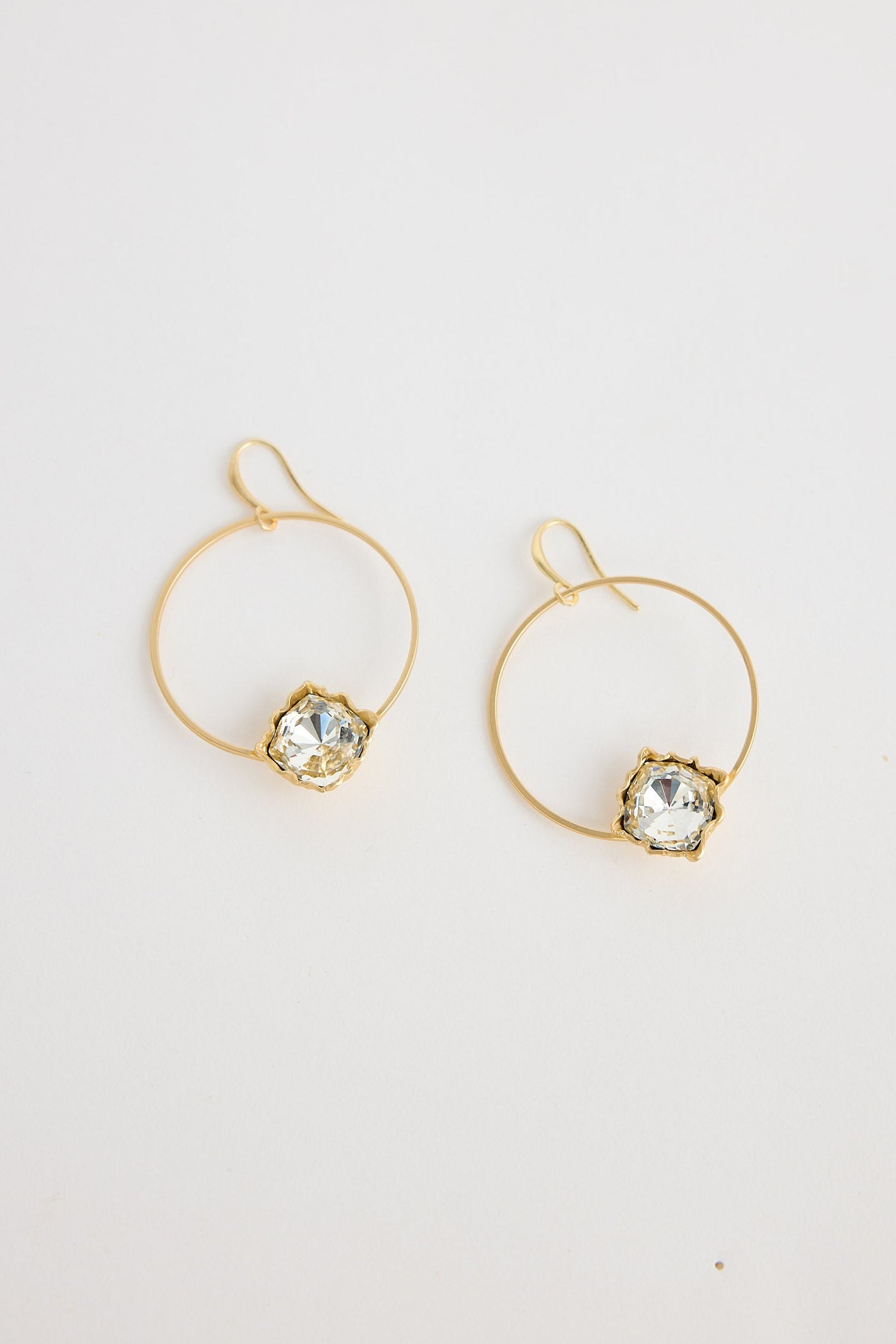 Gold hoop earrings with gemstones on a white background