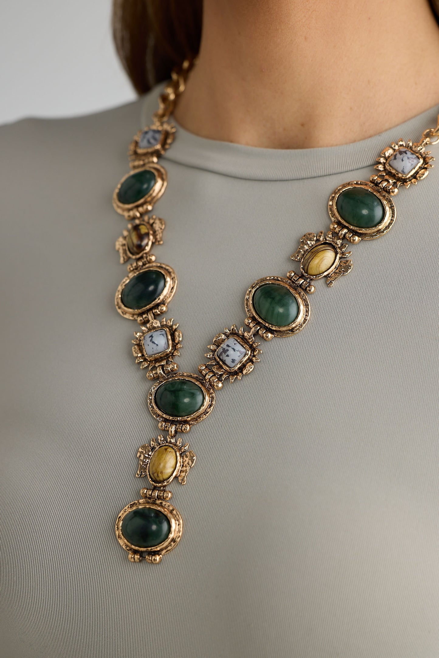 Necklace with green and gold stones on a plain background