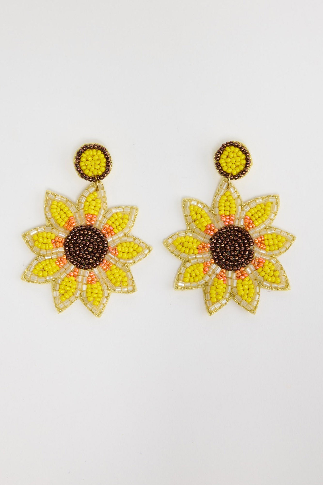 Pair of large beaded sunflower drop earrings with yellow and orange seed bead petals, a dark brown beaded centre and a round yellow beaded stud, laid flat on a white background