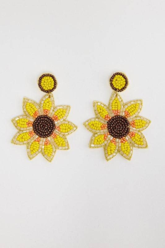 Pair of large beaded sunflower drop earrings with yellow and orange seed bead petals, a dark brown beaded centre and a round yellow beaded stud, laid flat on a white background