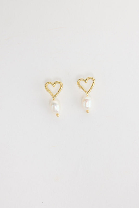 Pair of gold-tone open heart stud earrings with a single freshwater pearl drop and a small gold bead below, laid flat on a white background