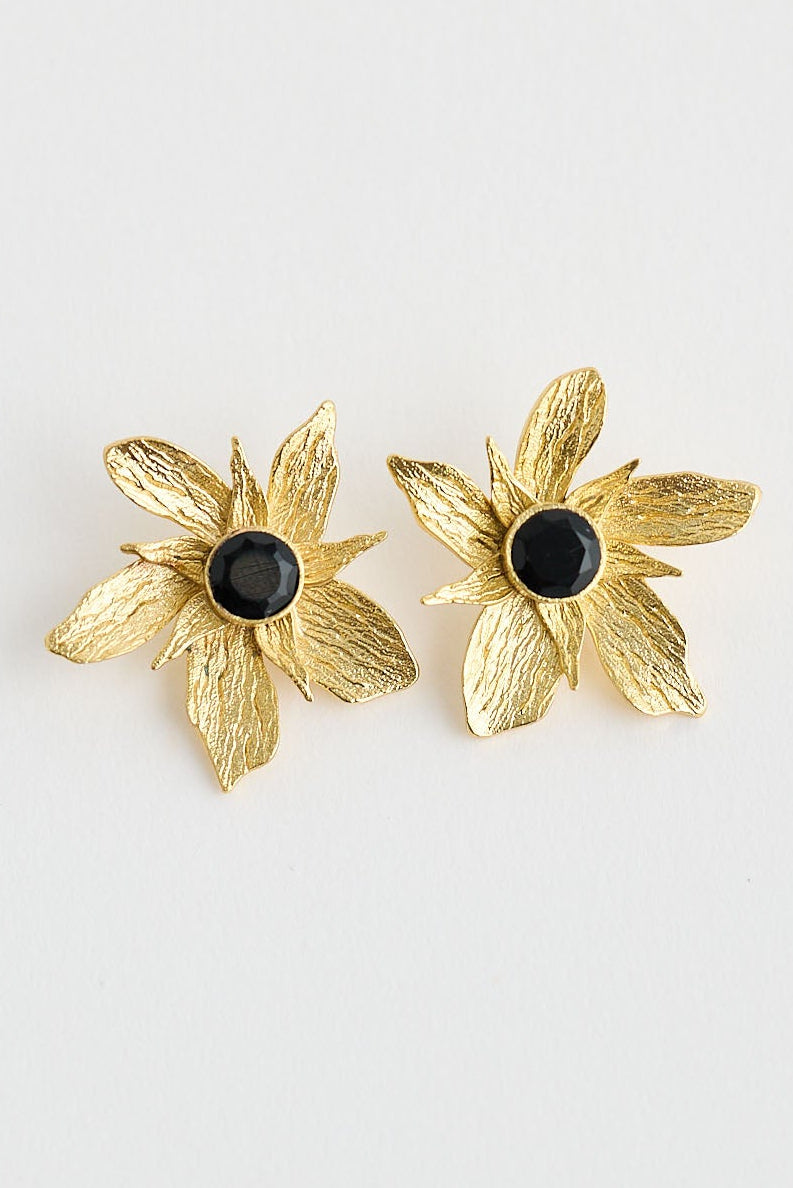 Gold flower-shaped earrings on a light gray background