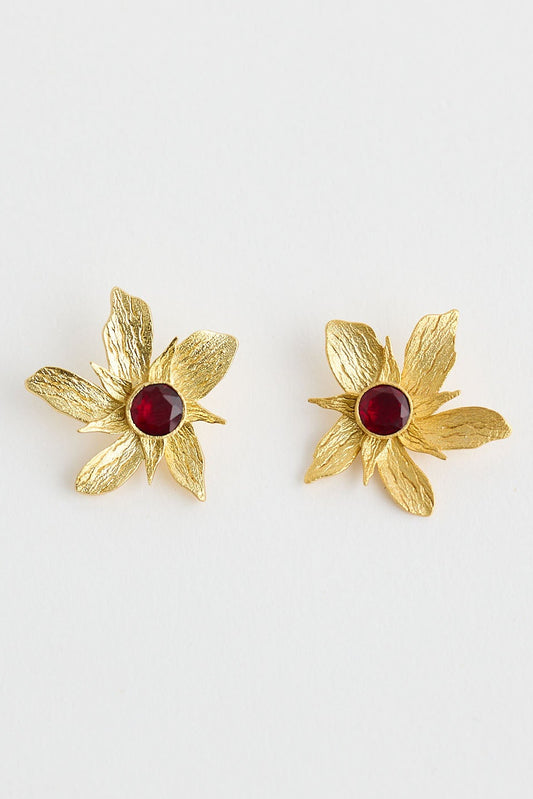 Gold flower-shaped earrings with red centers on a white background