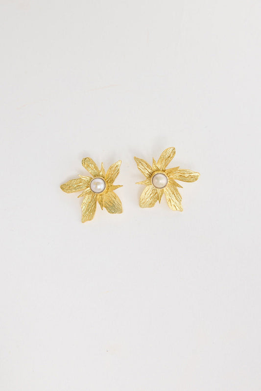 Pair of large gold-tone flower stud earrings with textured brushed petals and a pearl centre, laid flat on a white background