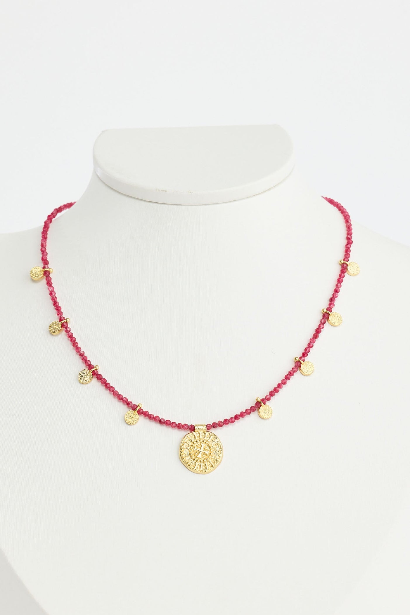 Necklace with red beads and gold accents on a white mannequin