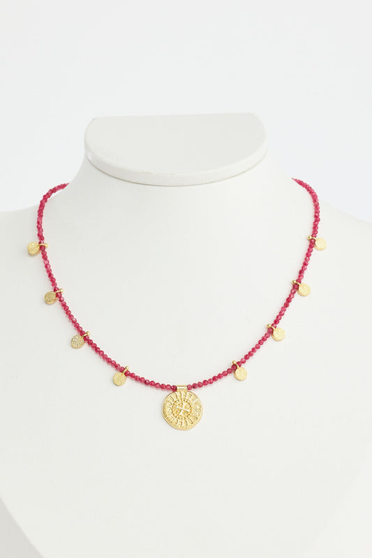 Necklace with red beads and gold accents on a white mannequin