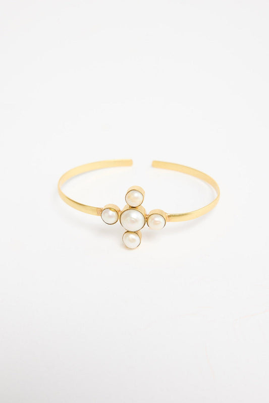 Open gold-tone cuff bracelet with a cross-shaped cluster of five freshwater pearls at the centre, shown at an angle on a white background