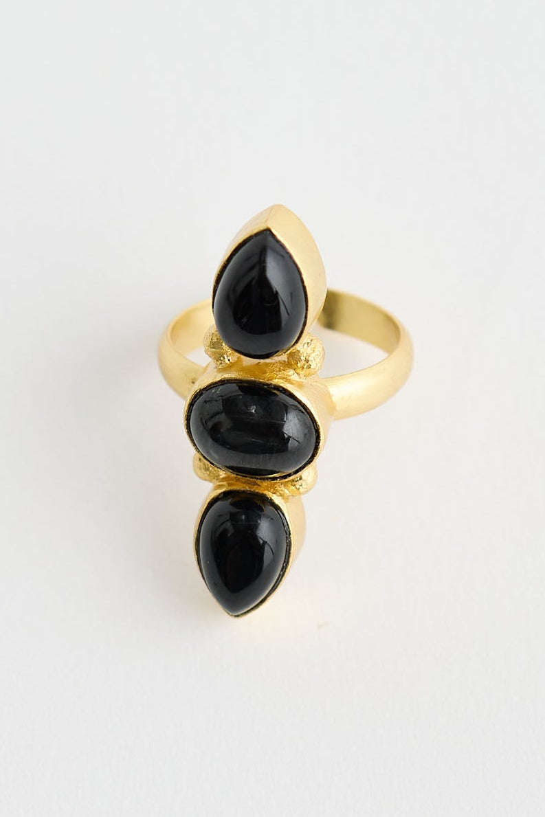 Gold ring with three black stones on a white background