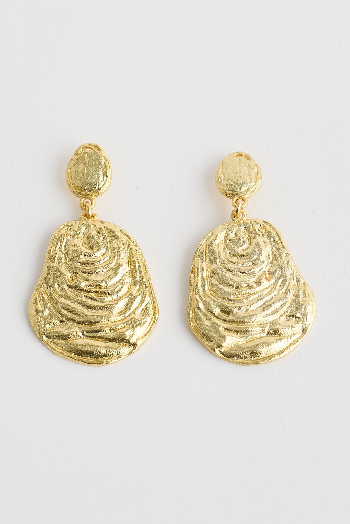 Close-up of gold oyster earrings earrings on white background.