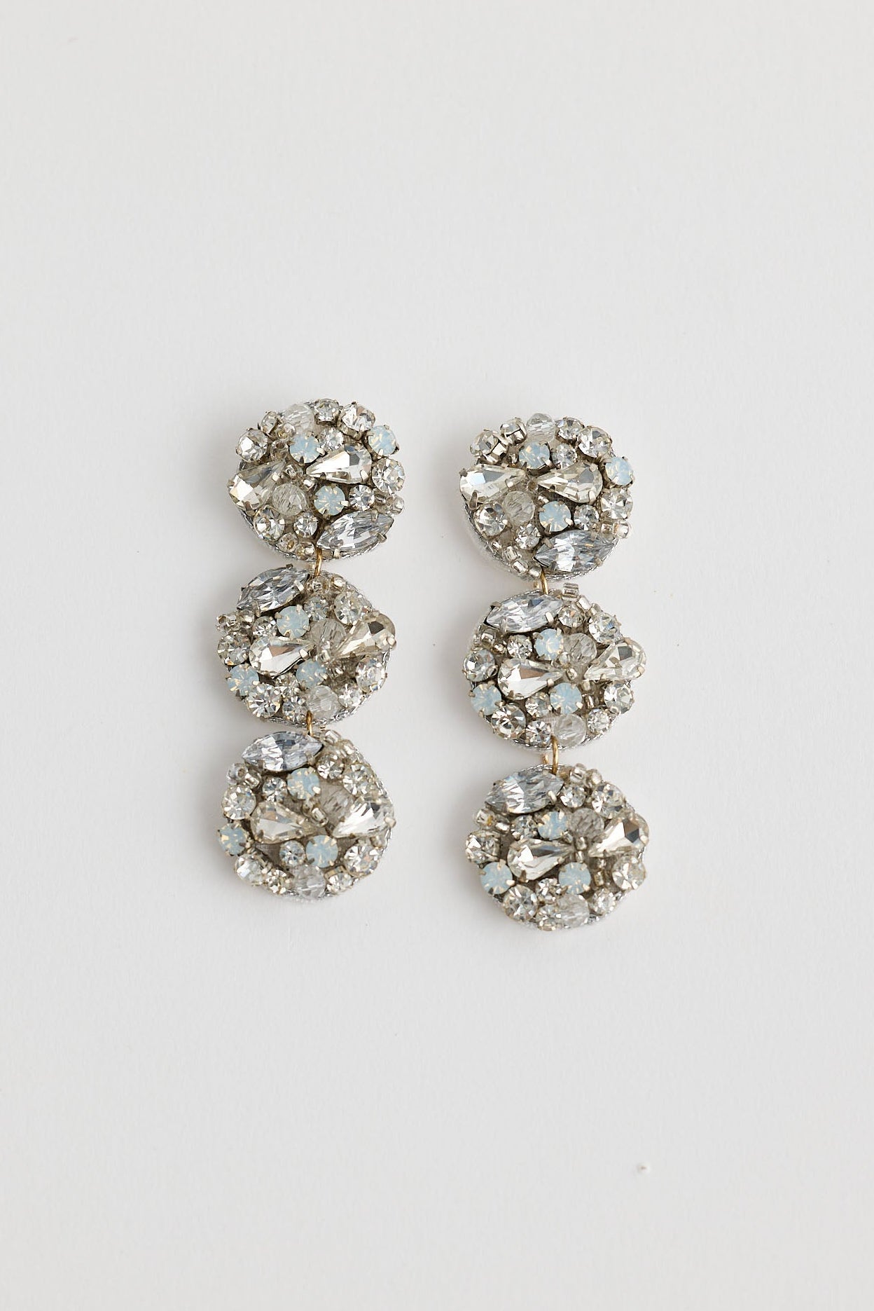 Pair of silver earrings with gemstones on a light gray background