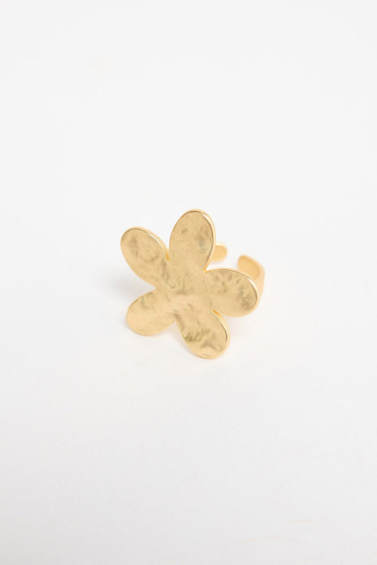 Gold-tone adjustable ring with a large daisy flower top featuring textured petals and a crystal centre, shown at an angle on a white background