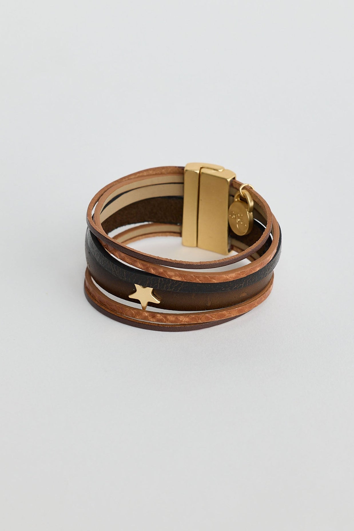 Multi-layered leather bracelet with gold clasp on a light gray background