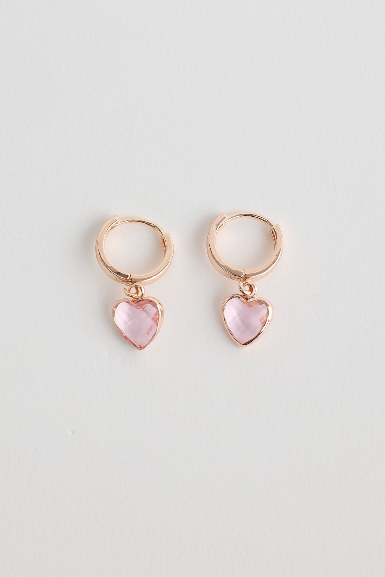 Close-up of rose gold adore earrings earrings on white background.