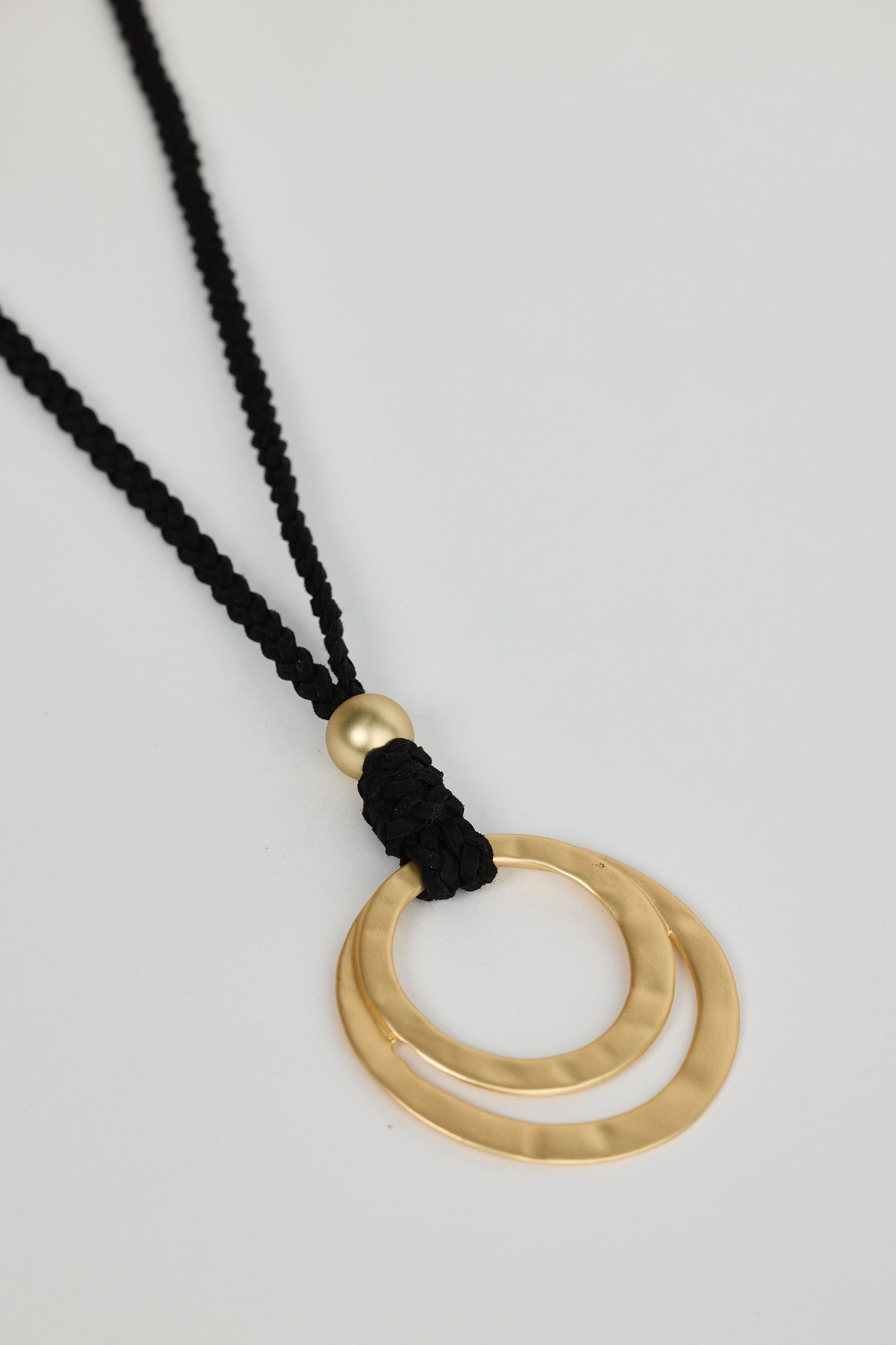 Close-up of black w gold double circle necklace necklace on white background.