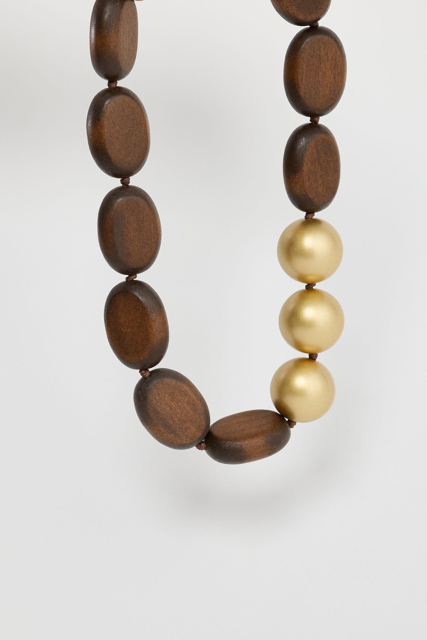 Close-up of wood w gold singer necklace necklace on white background.