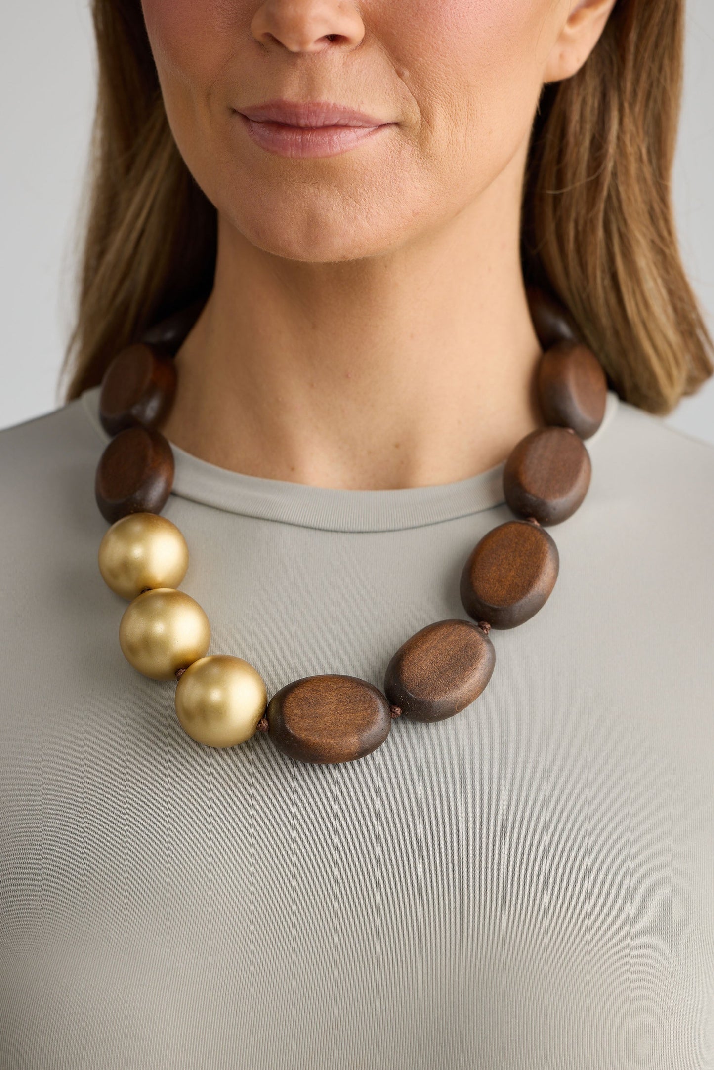 Close-up of wood w gold singer necklace necklace on white background.