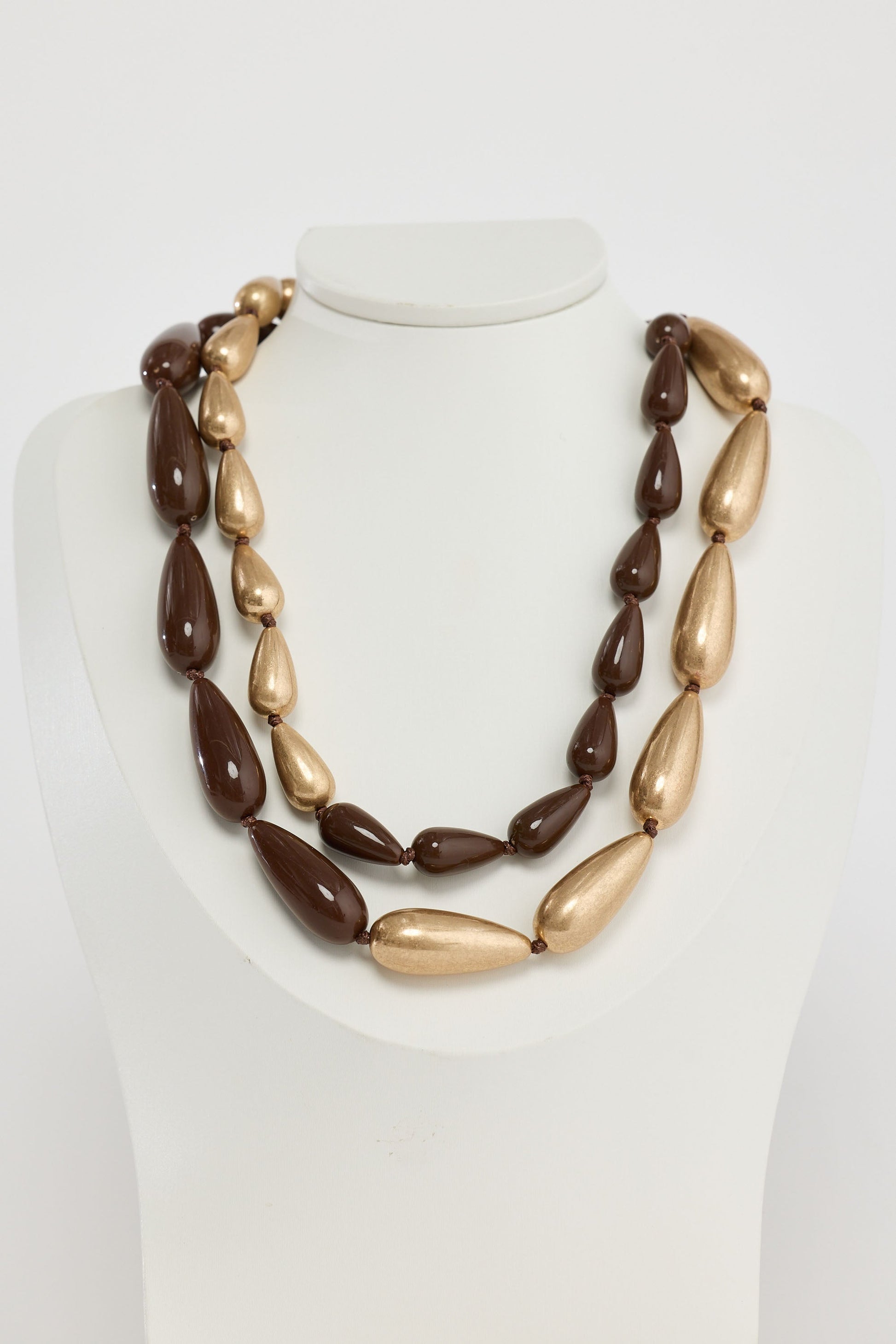 Close-up of wood w gold irina necklace necklace on white background.