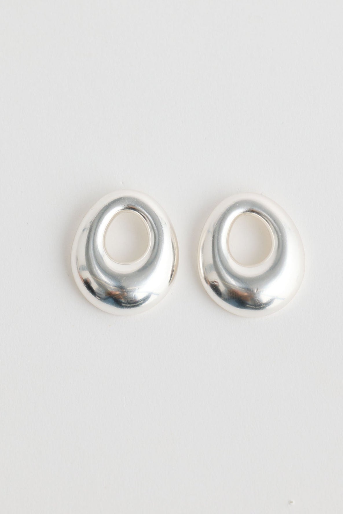 Close-up of silver jordan earrings earrings on white background.