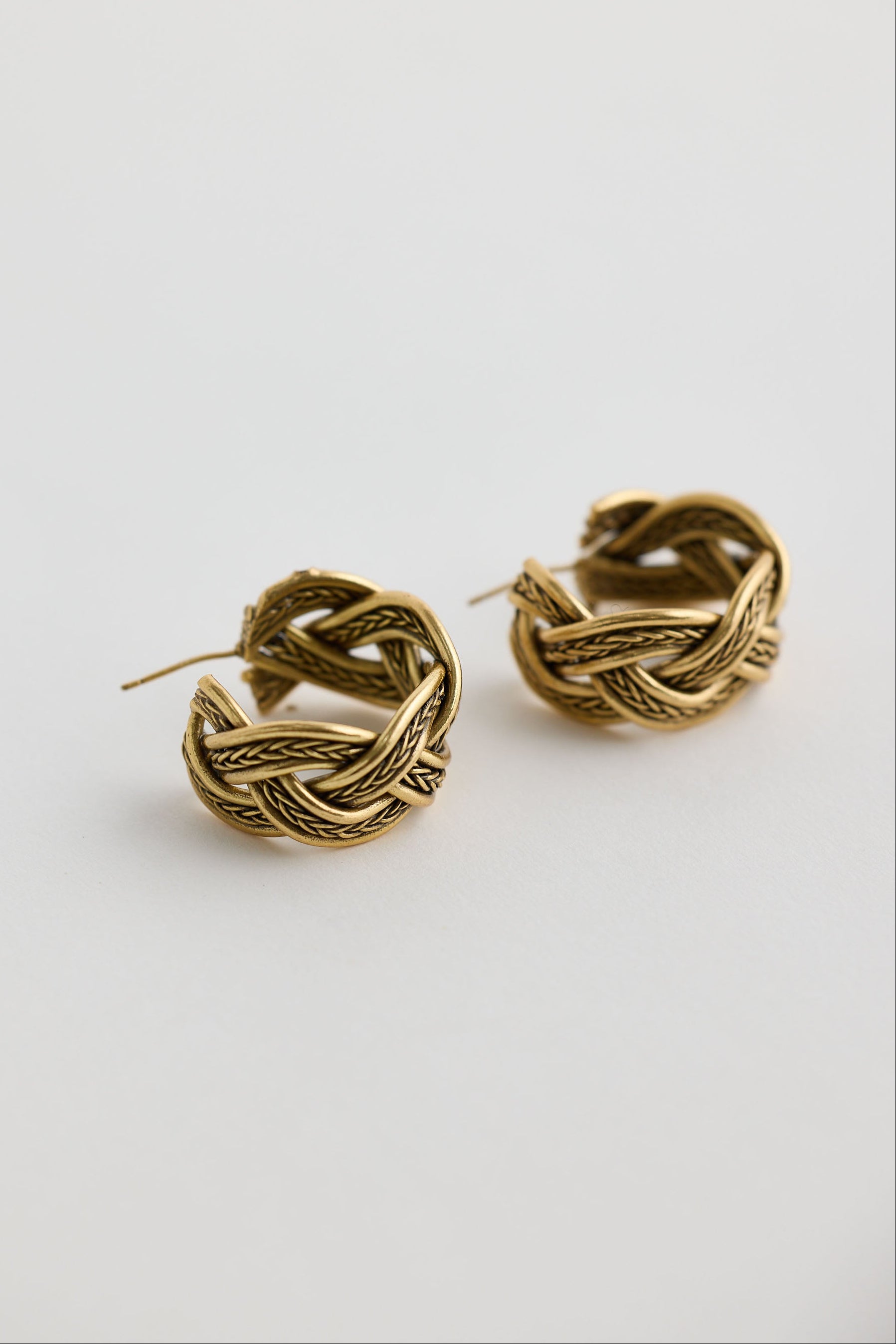 Close-up of gold casey earrings earrings on white background.