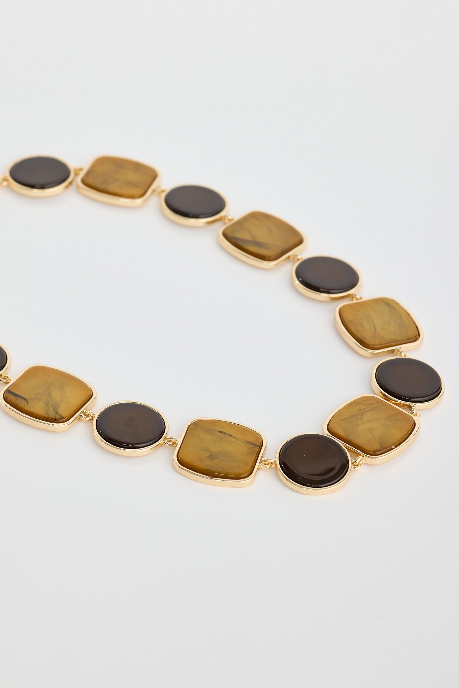 Necklace with gold and brown stone beads on a light gray background