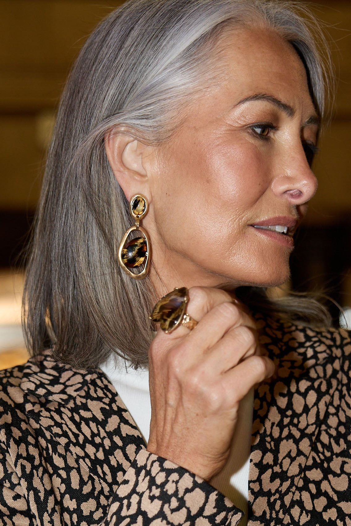 Woman wearing a leopard print outfit with gold jewelry indoors.