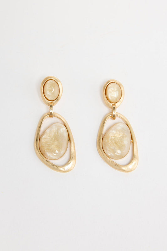 Pair of gold-tone drop earrings with a small oval cream resin stud and a large organic-shaped open gold hoop holding a cream resin stone, laid flat on a white background